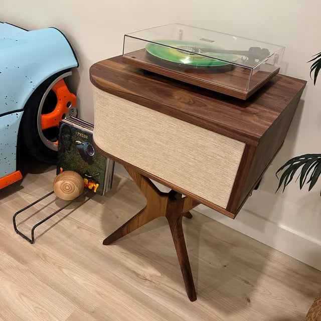 Wooden record player stand with a vinyl record on a turntable, surrounded by books and a toy car.